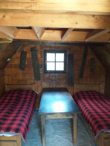 um quarto com duas camas num chalé de madeira em Koliba Kod Begija em Paljevine