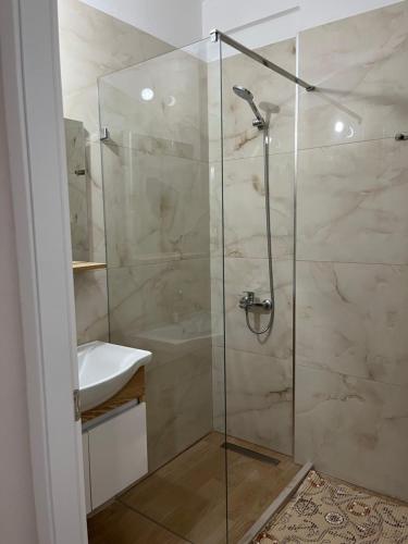 a bathroom with a glass shower with a sink at Lotus Apartments in Vlorë