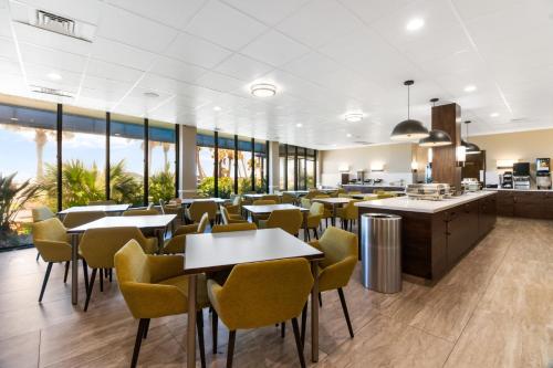 a restaurant with tables and chairs and windows at Beachfront Palms Hotel Galveston in Galveston