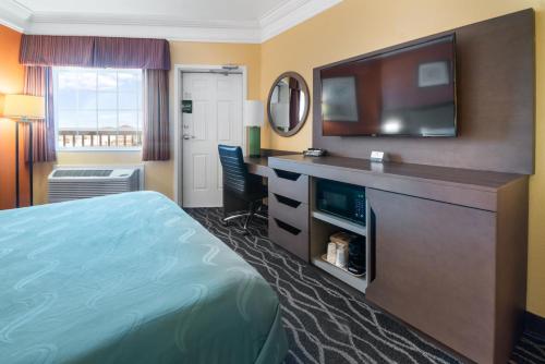 a hotel room with a bed and a flat screen tv at Quality Inn & Suites Galveston - Beachfront in Galveston