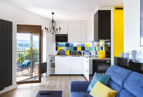 un salon avec un canapé bleu et une cuisine dans l'établissement Słoneczny apartament z widokiem na góry, à Szklarska Poręba