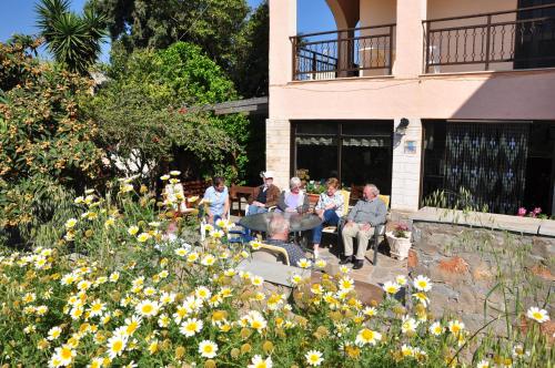 a group of people sitting on a bench in a garden at House Margot in Palekastron