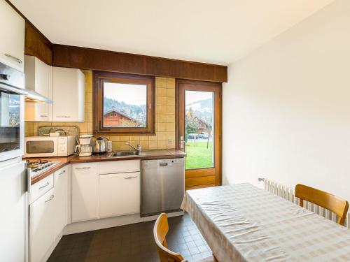une cuisine avec des armoires blanches, une table et une fenêtre dans l'établissement Appartement cosy 2P à Megève Jaillet - Proche pistes, Wi-Fi, parking, animaux acceptés - FR-1-453-91, à Megève