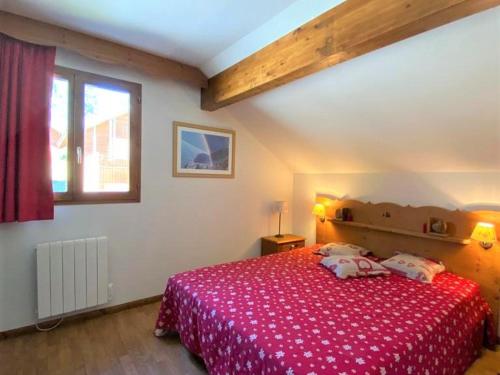 a bedroom with a bed with a red blanket and a window at Chalet La Joue du Loup, 3 pièces, 8 personnes - FR-1-504-3 in Le Dévoluy