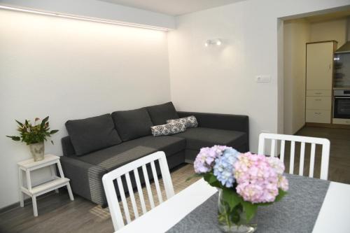a living room with a couch and a table with flowers at Apartma pri lipi in Bohinj