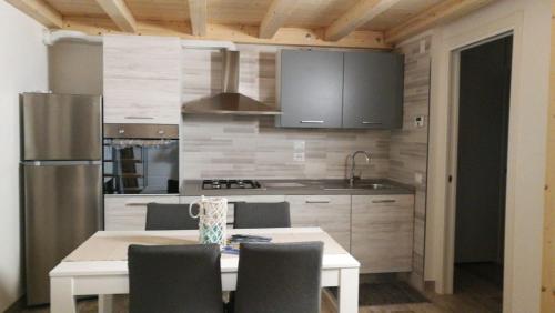 eine Küche mit einem Tisch mit Stühlen und einem Kühlschrank in der Unterkunft La Quercia in Cavallino-Treporti
