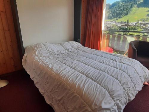 łóżko w sypialni z dużym oknem w obiekcie Studio à Morzine, 30m², 4 pers, balcon, parking, wifi - FR-1-524-73 w mieście Morzine