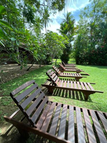 a row of wooden benches sitting in a park at Sandali Walauwa in Bentota