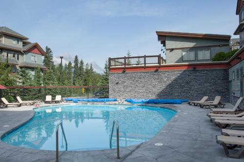 einen Pool mit Stühlen und ein Haus in der Unterkunft Lodges at Canmore in Canmore