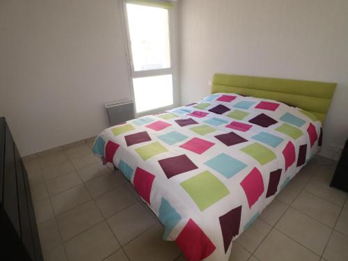 une chambre avec un lit avec une couette colorée dans l'établissement Appartement T2 avec Terrasse, Parking et Piscine à Sète, proche Plage - FR-1-472-117, à Sète
