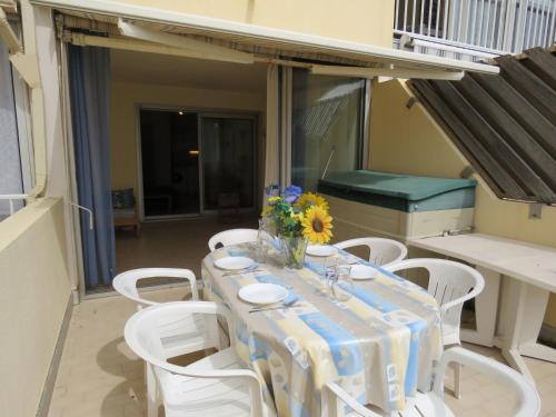 d'une table avec des chaises blanches et un vase de fleurs sur le balcon. dans l'établissement Charmant T2 de 40m² en front de mer avec loggia, terrasse et parking privé - Sète - FR-1-472-127, à Sète