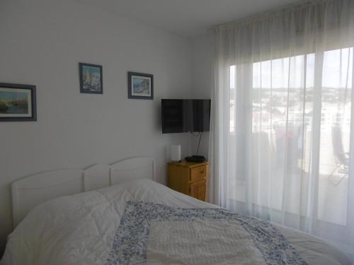 une chambre avec un lit, une télévision et une fenêtre dans l'établissement T2 cabine 35m² dernier étage, terrasse, parking - FR-1-472-136, à Sète