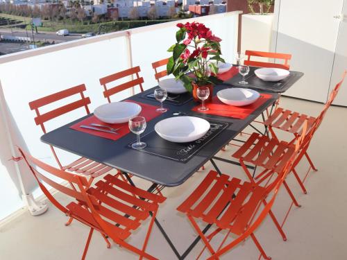 une table noire avec des chaises, des assiettes et un vase de fleurs dans l'établissement T3 75m² avec Terrasse et Double Parking à Sète - FR-1-472-141, à Sète