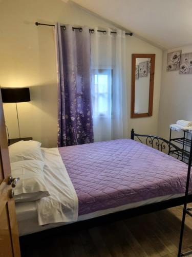 a bedroom with a bed with a purple blanket and a window at Wooden house corfu in Halikounas