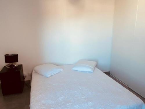 - une petite chambre avec un lit et 2 oreillers blancs dans l'établissement T2 43m² dernier étage avec terrasse et parking à Sète - FR-1-472-148, à Sète