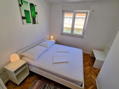 een wit bed in een kamer met een raam bij Omiš City Apartment in Omiš