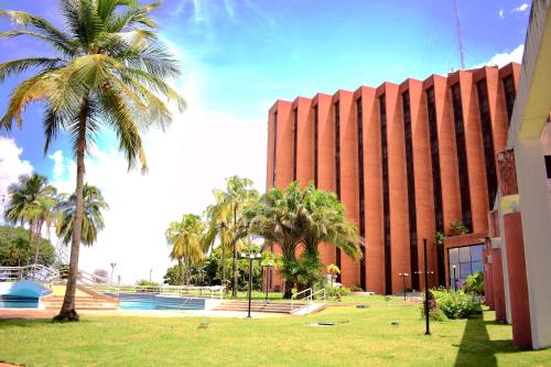 a large red building with palm trees in front of it at Tibisay Hotel Maturin in Maturín