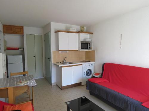 un salon avec un canapé rouge et une cuisine dans l'établissement Studio à Sète avec terrasse, cuisine équipée et vue marina - FR-1-472-149, à Sète