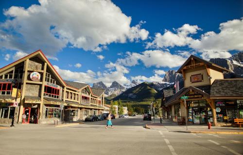 a woman walking down a street in a town with mountains at Lodges at Canmore in Canmore