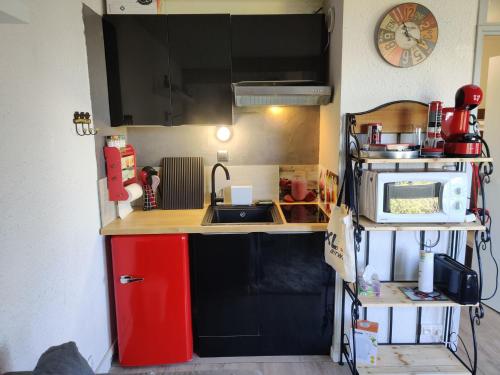 une petite cuisine avec un évier et un micro-ondes dans l'établissement Studio lumineux à Pra-Loup, proche pistes, galerie commerciale et parking privé. - FR-1-165A-109, à Uvernet