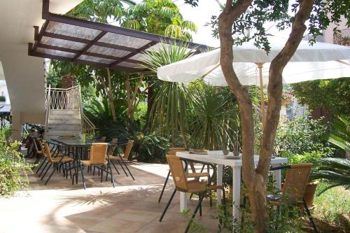 een patio met tafels en stoelen en een parasol bij Mandarinoarancio in Alezio