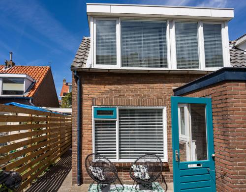 a house with two chairs and a blue door at Tiny Beachhouse Noordwijk in Noordwijk