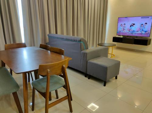 - un salon avec une table, des chaises et une télévision dans l'établissement New Cozy Mvista Homestay at Bayan Lepas Factory Area, à Bayan Lepas