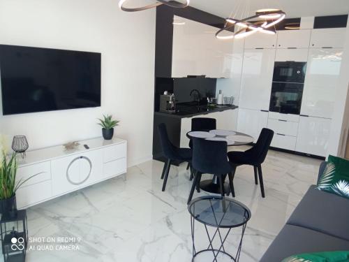 uma cozinha e sala de estar com mesa e cadeiras em Apartament z widokiem na morze w kompleksie Hevenia em Rewal