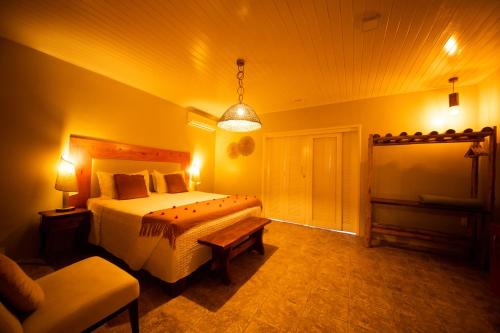 a bedroom with a bed and a couch and a lamp at Pousada Vila Sagui in Maragogi