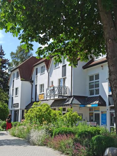 un grande edificio bianco con un albero in primo piano di Appartment Relaxtage a Zingst