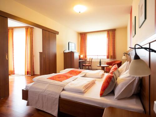 ポイスドルフにあるHotel Neustifterのベッドルーム1室(白いシーツと赤い枕の大型ベッド1台付)