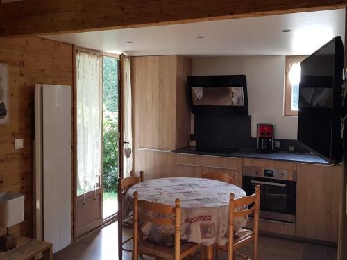 une petite cuisine avec une table et un réfrigérateur dans l'établissement Chalet rénové, cozy et bien équipé avec jardin - Proche Golf et Navette gratuite Pra-Loup - FR-1-165A-145, à Barcelonnette