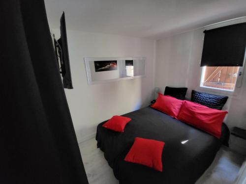 - une chambre avec un lit noir et des oreillers rouges dans l'établissement le zen du cap d'agde, au Cap d'Agde