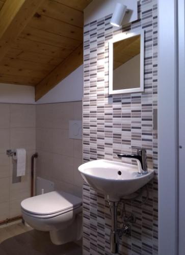 a bathroom with a sink and a toilet and a mirror at Dreaming Feriolo - mansarded apartment by Danilo Apartments in Baveno
