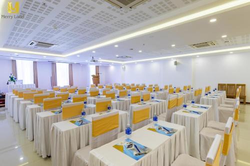 a large room with white tables and chairs at Merry Land Hotel Da Nang in Da Nang