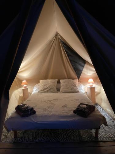 a bed in a tent with two bags on it at Camping Mon Repos in Montmaur