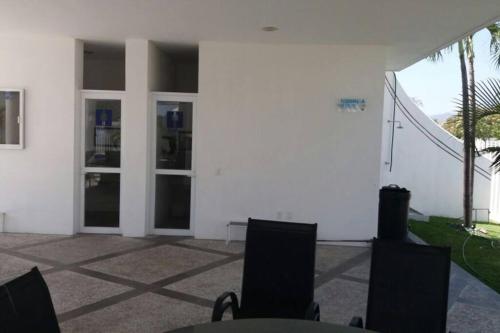 a patio with chairs and a white building at Casa Diamante Azul in Manzanillo