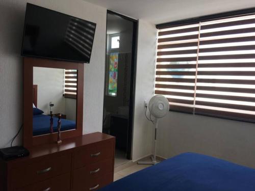 a bedroom with a tv and a dresser with a mirror at Casa Diamante Azul in Manzanillo
