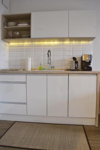 a kitchen with white cabinets and a sink at Sopotinn Apartment in Sopot