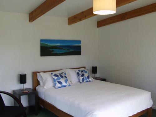Un dormitorio con una cama blanca con almohadas azules y blancas en Cabbage Tree Chalet, en Parapara 