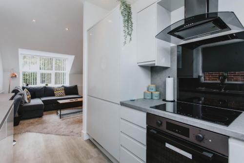 a kitchen with a stove top oven next to a living room at 1 Bed Stylish City Flat 2nd Floor close to City Centre with free parking, king size bed & Wi-Fi in Nottingham