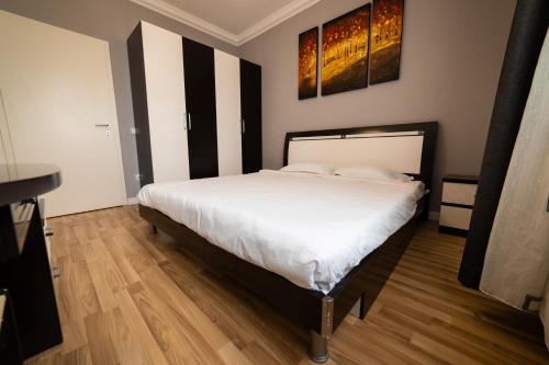 a bedroom with a large bed with white sheets at CedarTREE Prishtina in Prishtinë