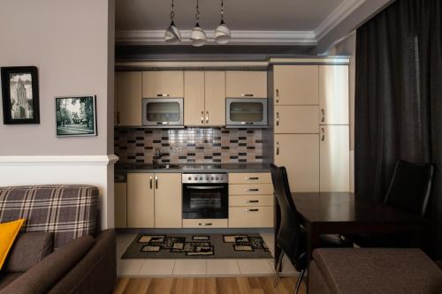 a kitchen with a couch and a table and a stove at CedarTREE Prishtina in Prishtinë