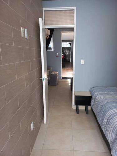 a bedroom with a bed and a door leading to a hallway at Apartamento a minutos caminando del Aeropuerto CDMX Terminal 1 in Mexico City