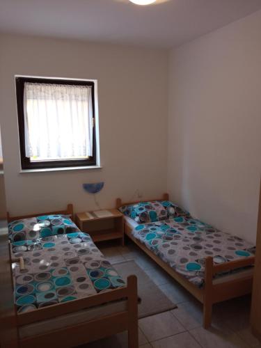 two beds in a room with a window at Apartmani Hotko in Sveti Juraj