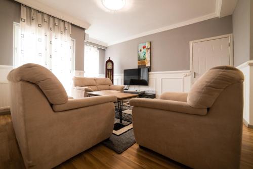 a living room with two chairs and a television at CedarTREE Prishtina in Prishtinë