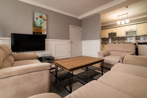 a living room with two couches and a tv at CedarTREE Prishtina in Prishtinë
