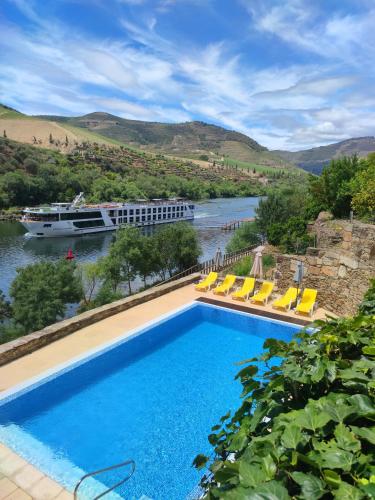 a swimming pool next to a river with a cruise ship at Hotel Casa do Tua in Foz Tua
