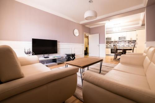 a living room with a couch and a tv at CedarTREE Prishtina in Prishtinë