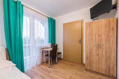 1 dormitorio con escritorio y cortina verde en Willa Nova, en Polańczyk
